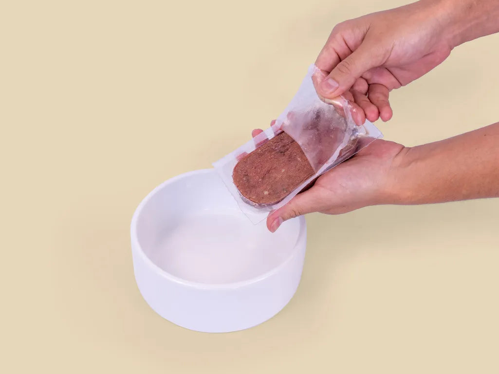 Opening a Big Dog Combo raw cat food patty over a bowl