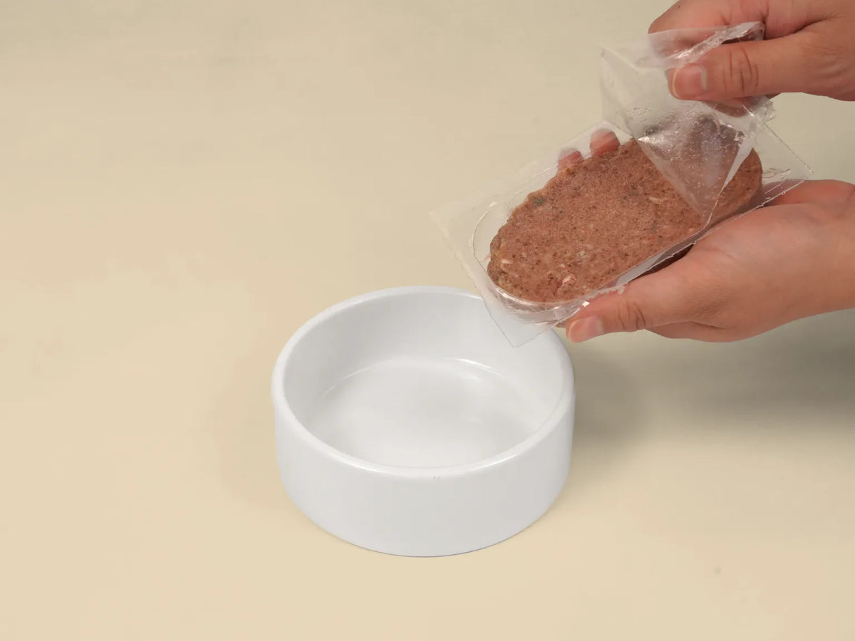 Opening a Big Dog Turkey raw cat food patty over a bowl