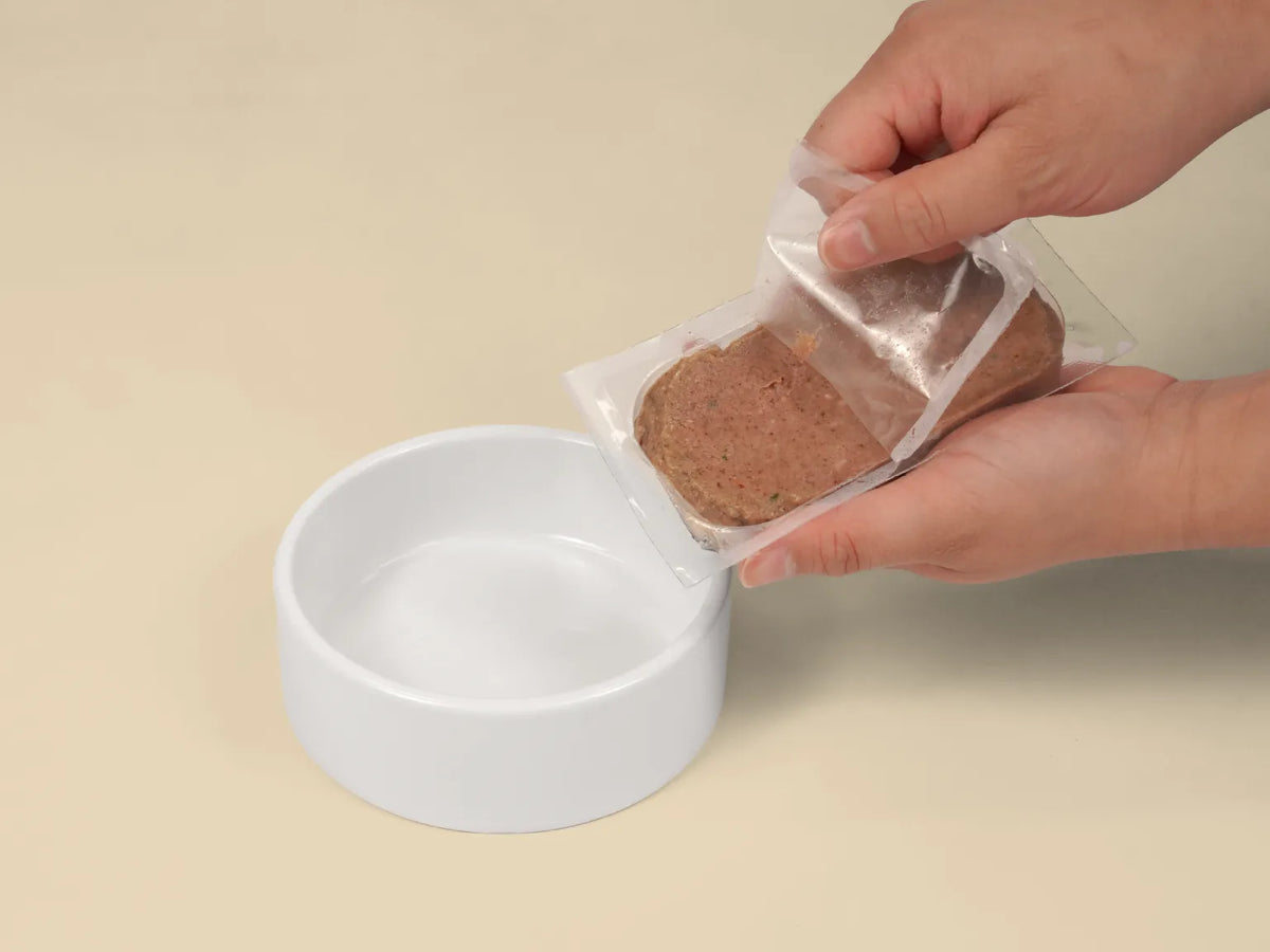 Opening a Big Dog Chicken raw cat food patty over a bowl