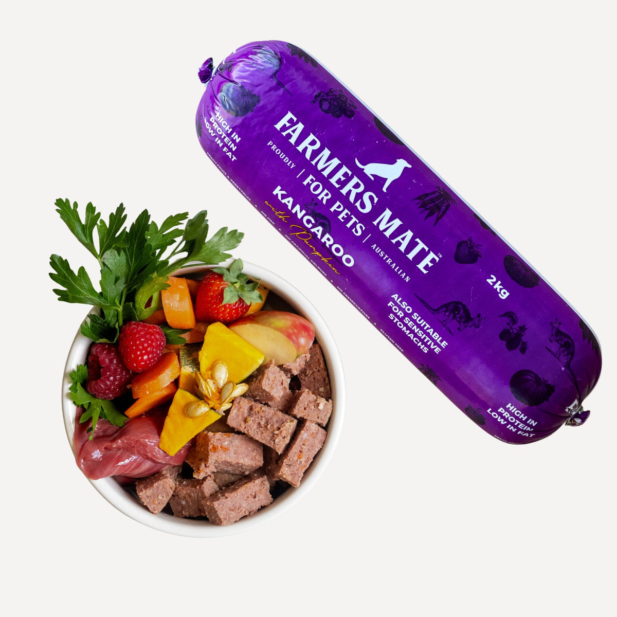 Farmers Mate for Pets Kangaroo & Pumpkin Roll 2 kg beside a bowl of sliced roll with fresh fruit and vegetables