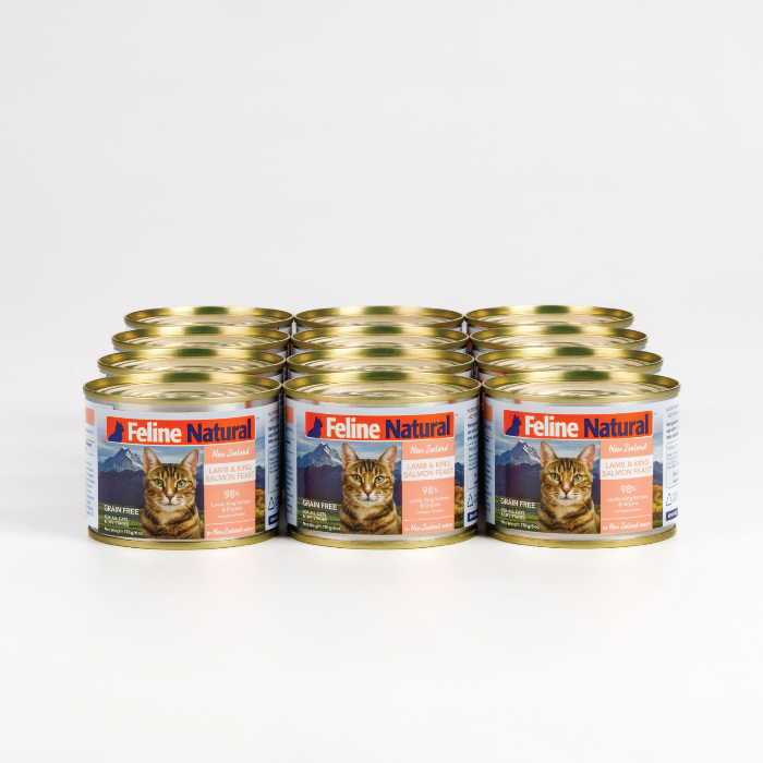 A can of Feline Natural Lamb and Salmon wet cat food. The can is labeled with an image of a cat and the New Zealand landscape, highlighting the natural ingredients and grain-free nature of the product.